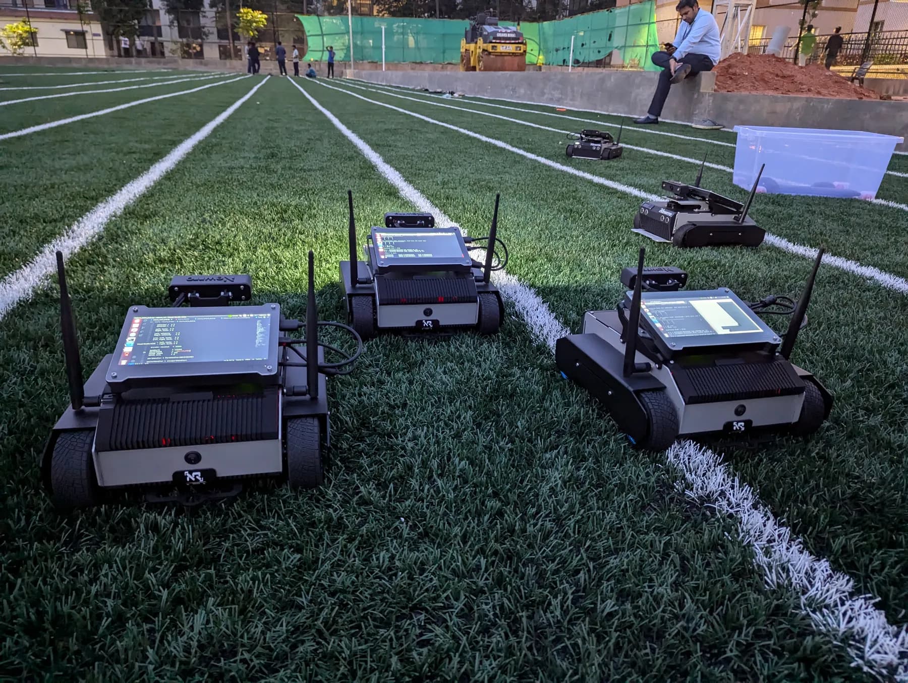 Several ARJUNA robots running navigation tests on an outdoor turf field